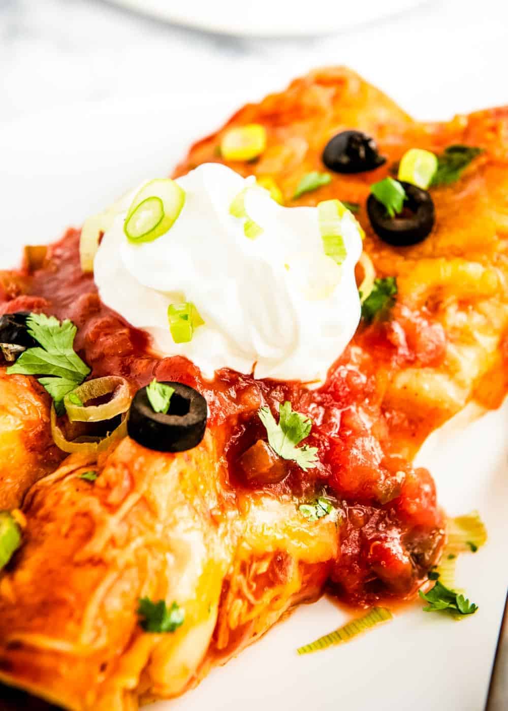 Close up of beef enchiladas with toppings.