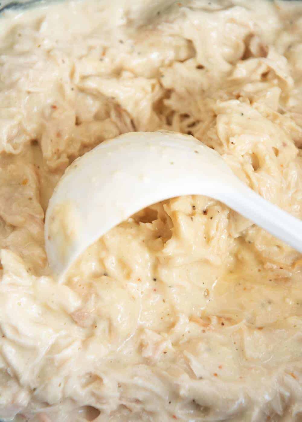 Scooping creamy Italian chicken with ladle.