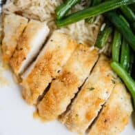 parmesan crusted chicken sliced on a plate with green beans and rice