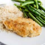 A plate of parmesan crusted chicken, green beans and rice