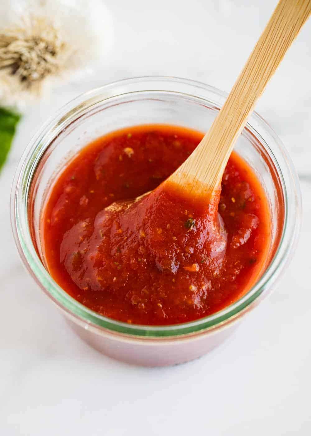 Pizza sauce in a jar with wooden spoon.