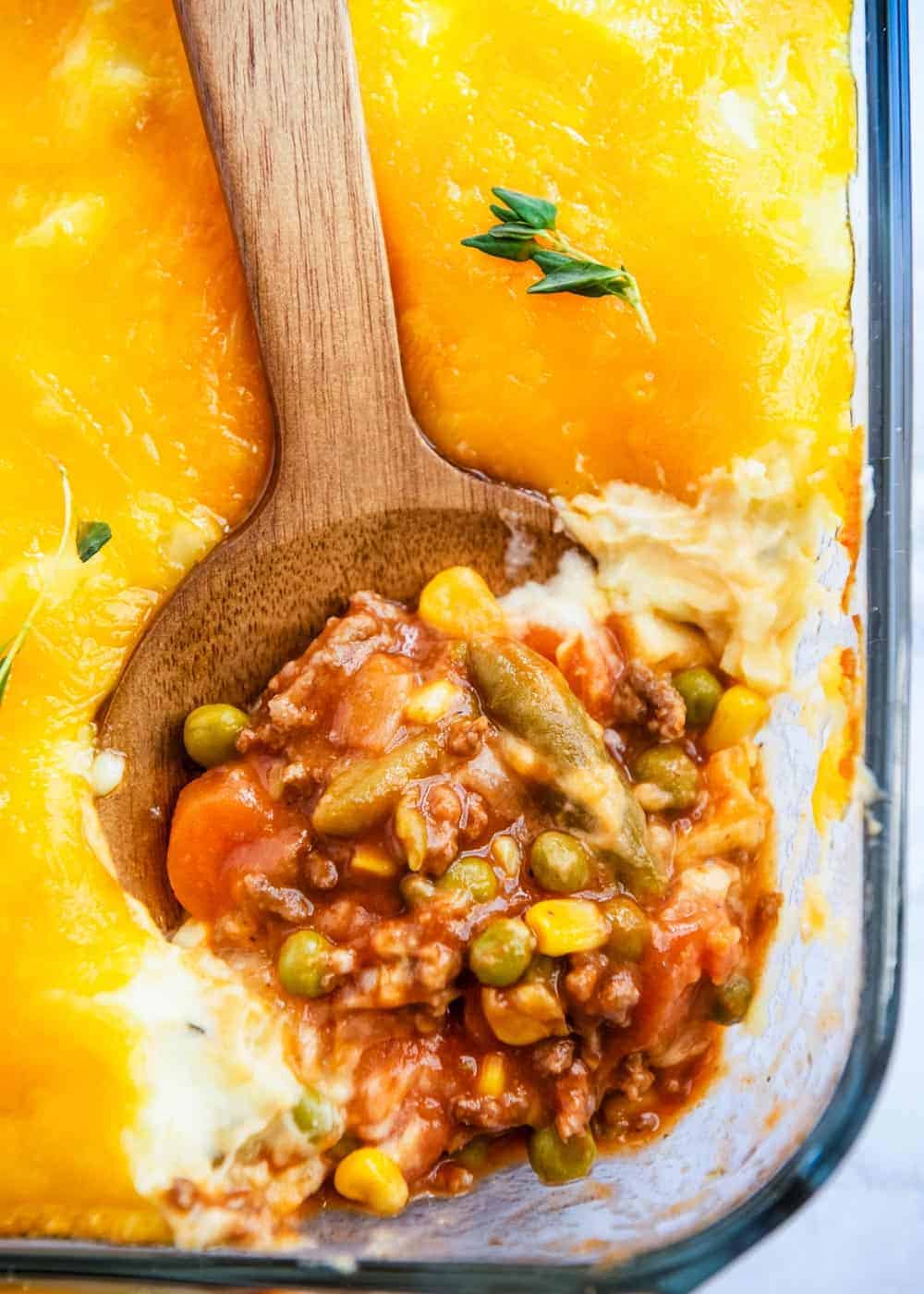 Shepherd's pie being dished out of a casserole dish.