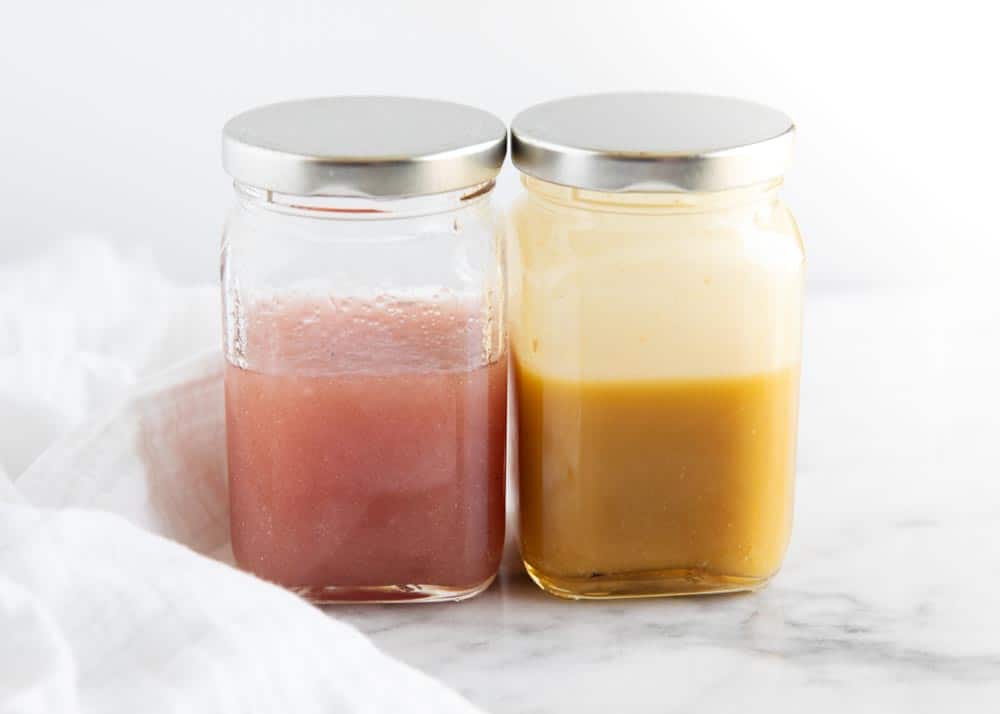 Two jars of vinaigrette dressing on counter.