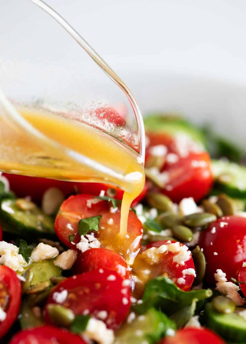 Pouring vinaigrette over chopped salad.