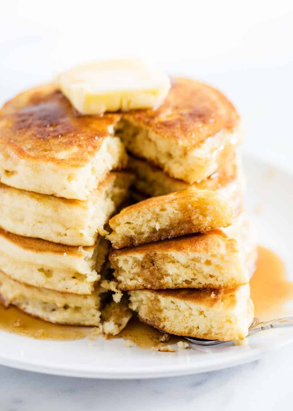 Cutting into stack of buttermilk pancakes with a fork.