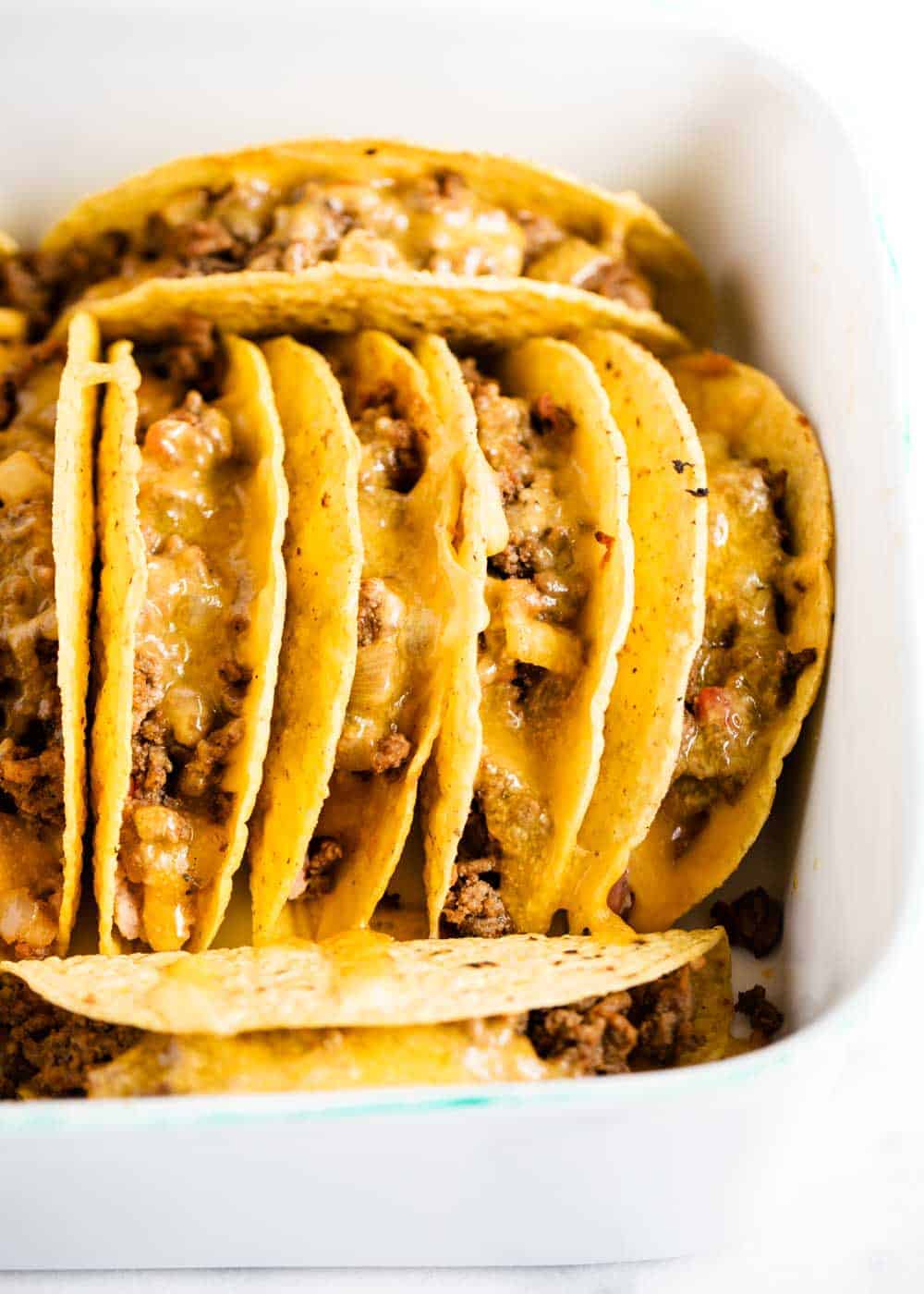 Ground beef tacos in pan with melted cheese on top.