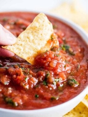 Dipping a chip into restaurant style salsa in a bowl.