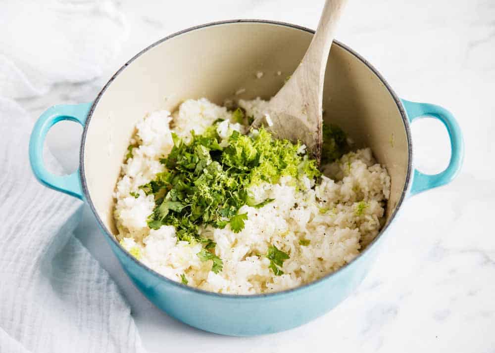 Making cilantro lime rice in a blue pan with a wooden spoon.