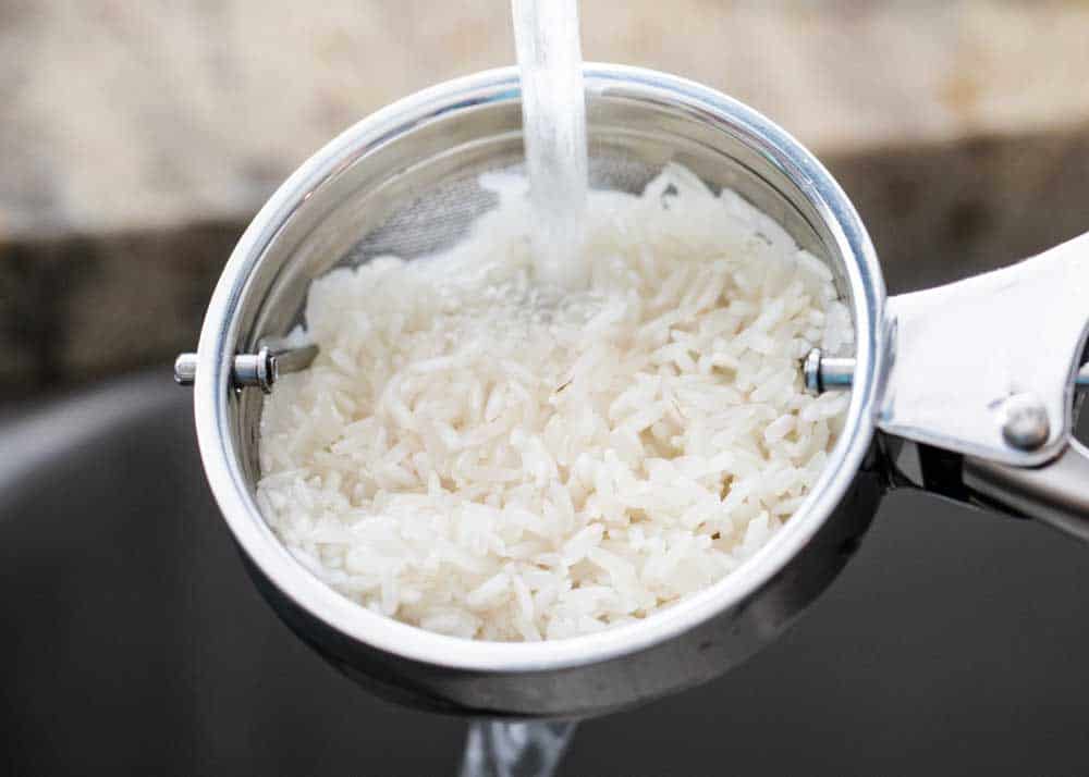 washing white rice in a strainer