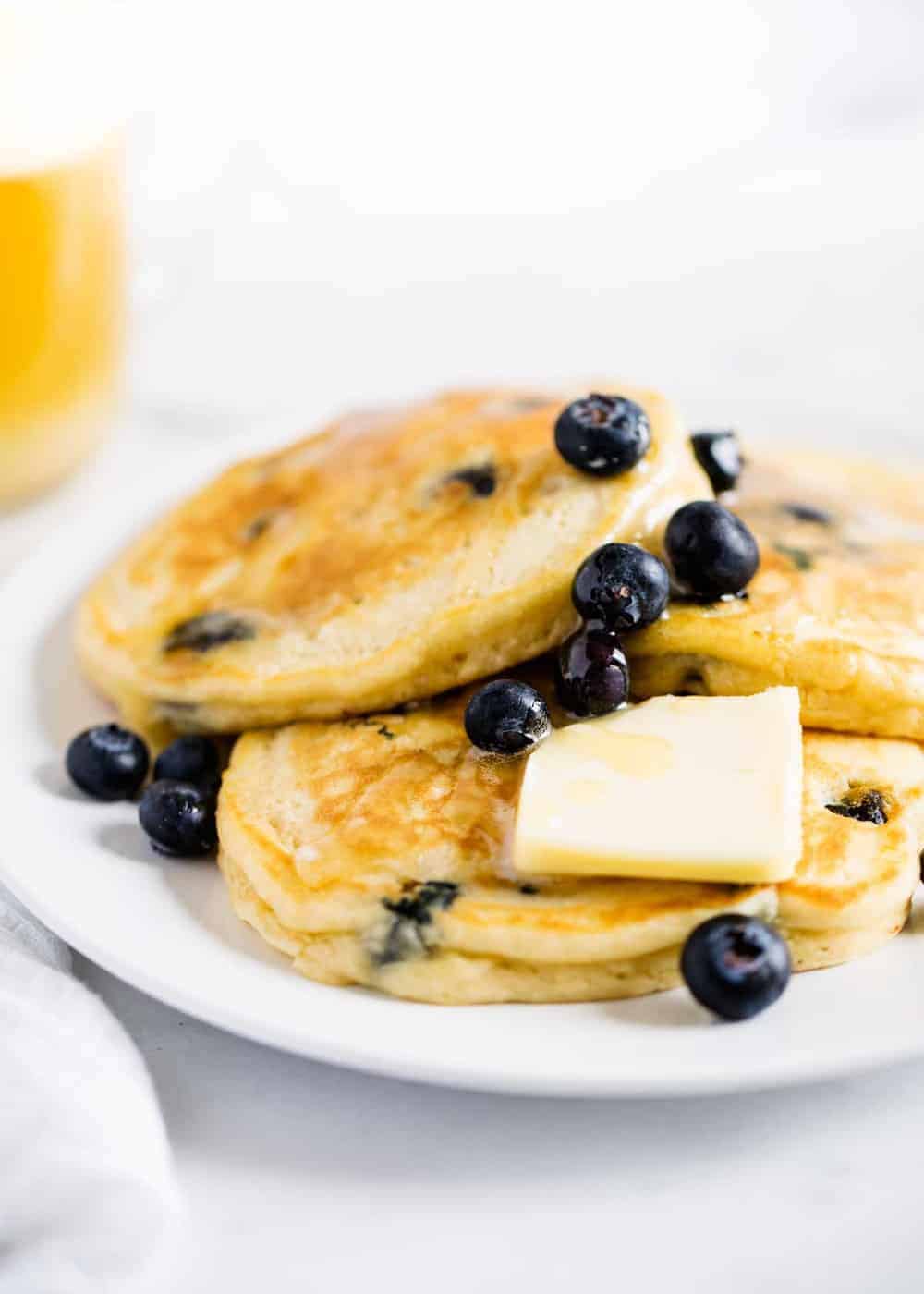 Blueberry pancakes on plate with butter and syrup.