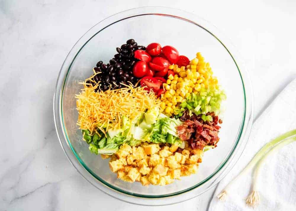 Cornbread salad ingredients in a glass bowl.