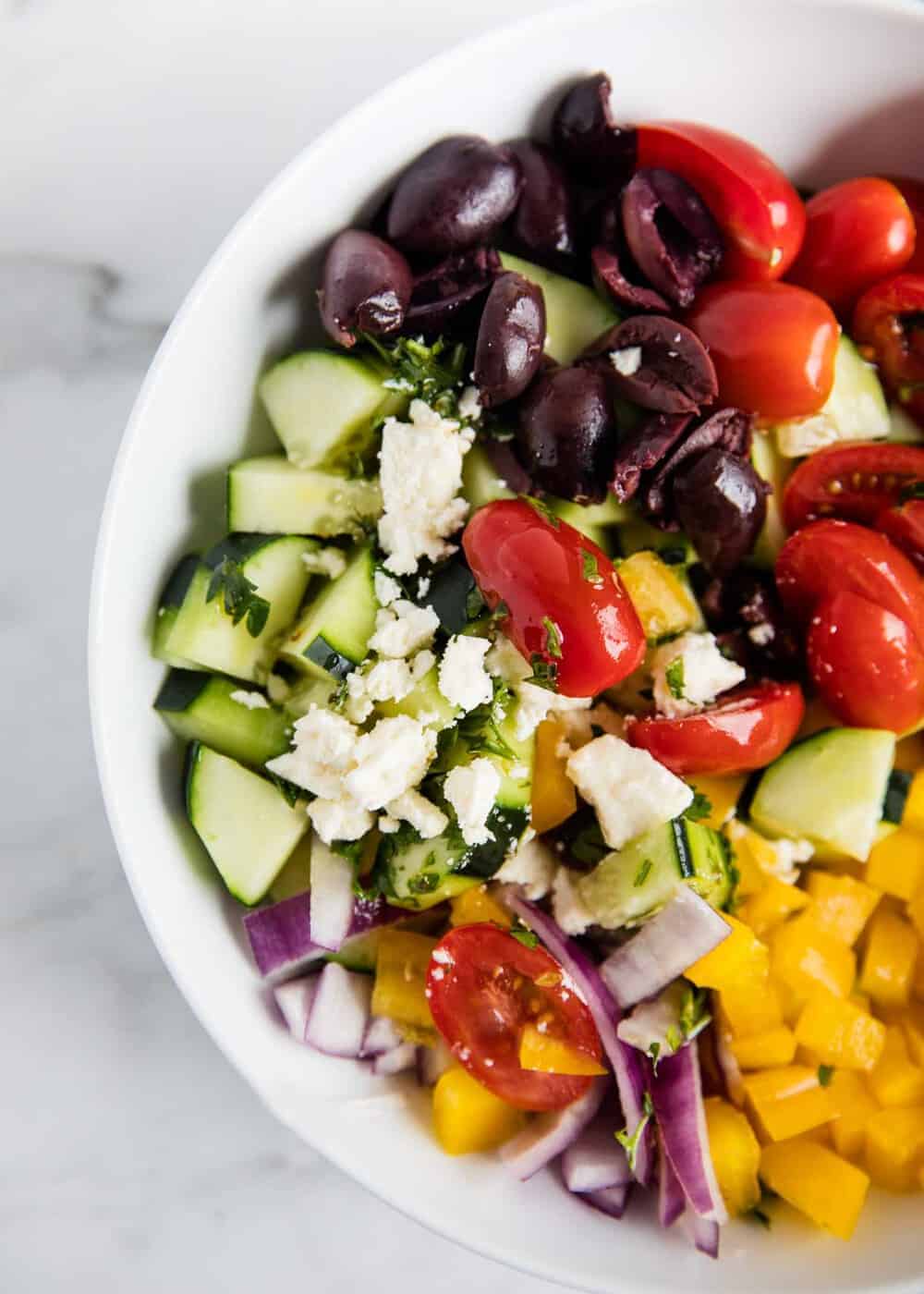 Greek salad in a white bowl.