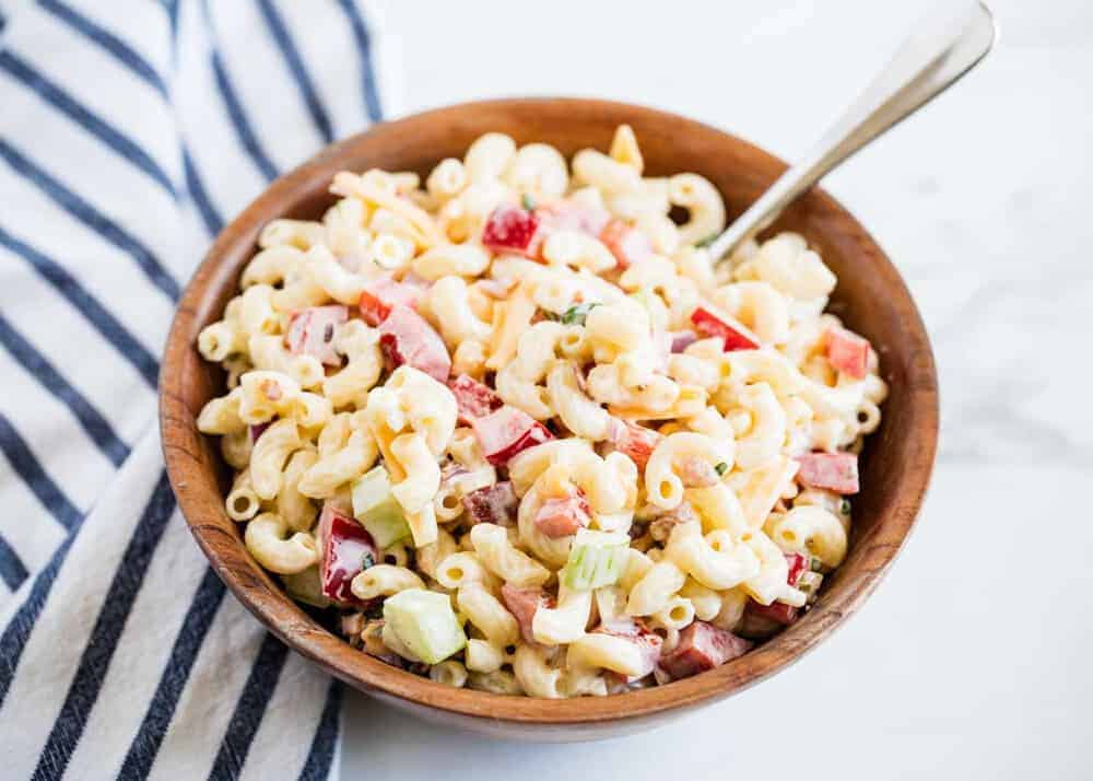 Macaroni salad in a wooden bowl with a spoon.