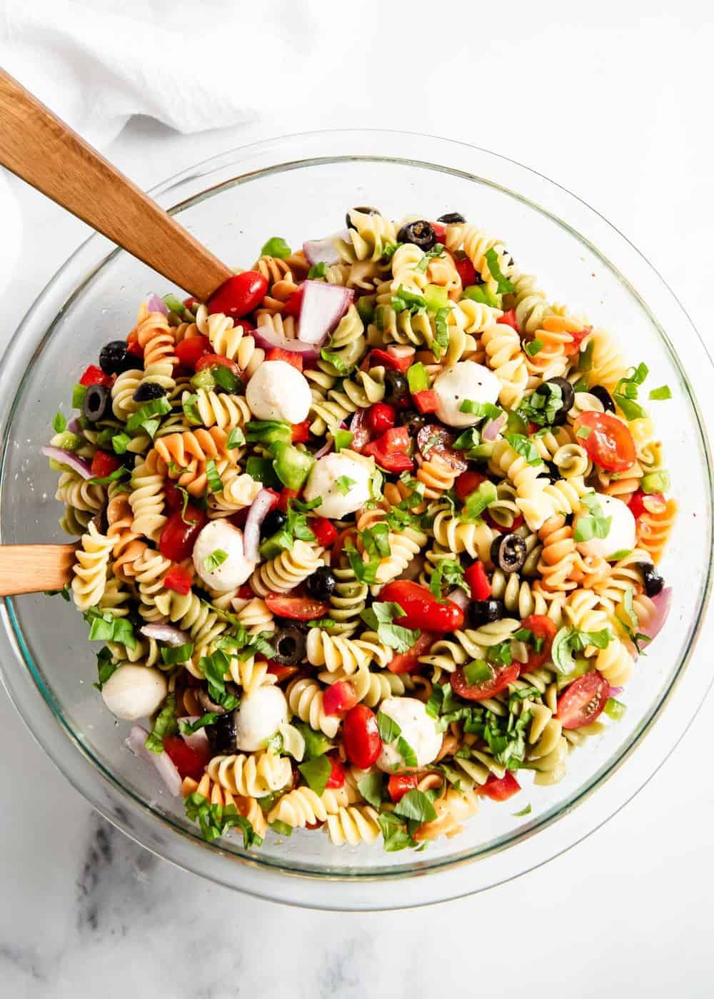 Pasta salad in bowl with wooden spoons.