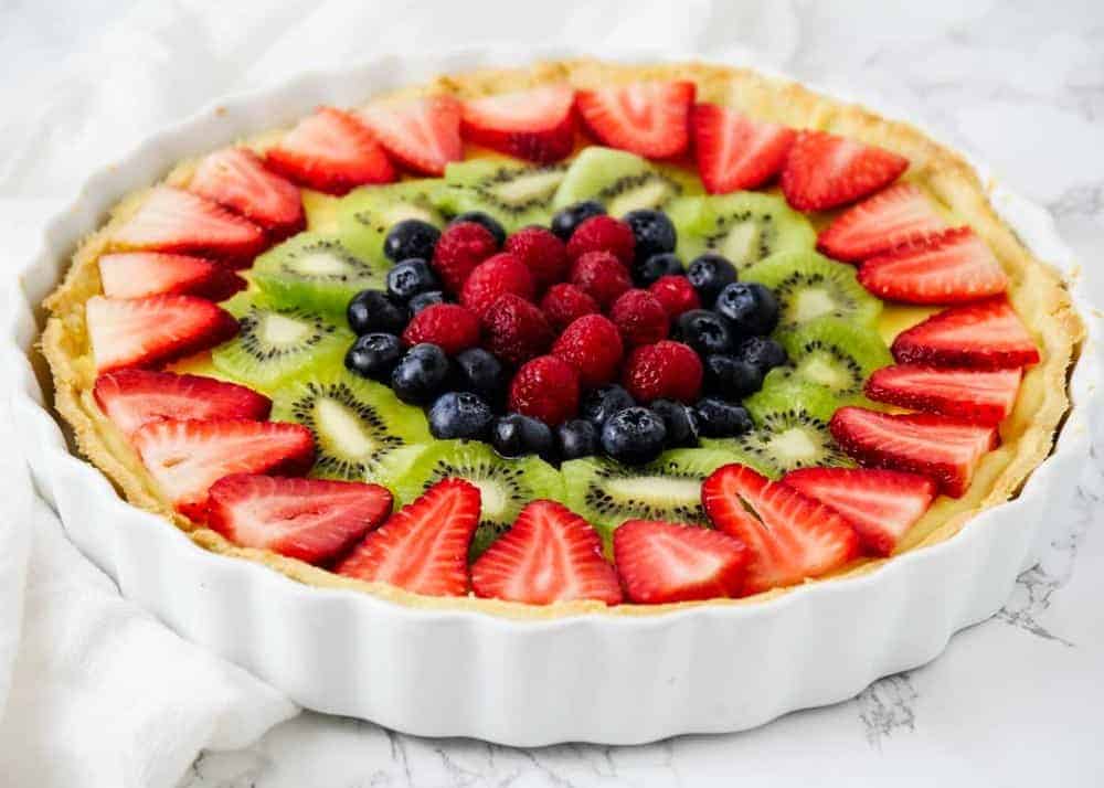 Each bite of this fresh fruit tart is a mix of crumbly sweet crust, smooth and decadent custard and juicy fresh berries! This fruit tart recipe is the perfect refreshing treat for warmer weather! fruit tart recipe