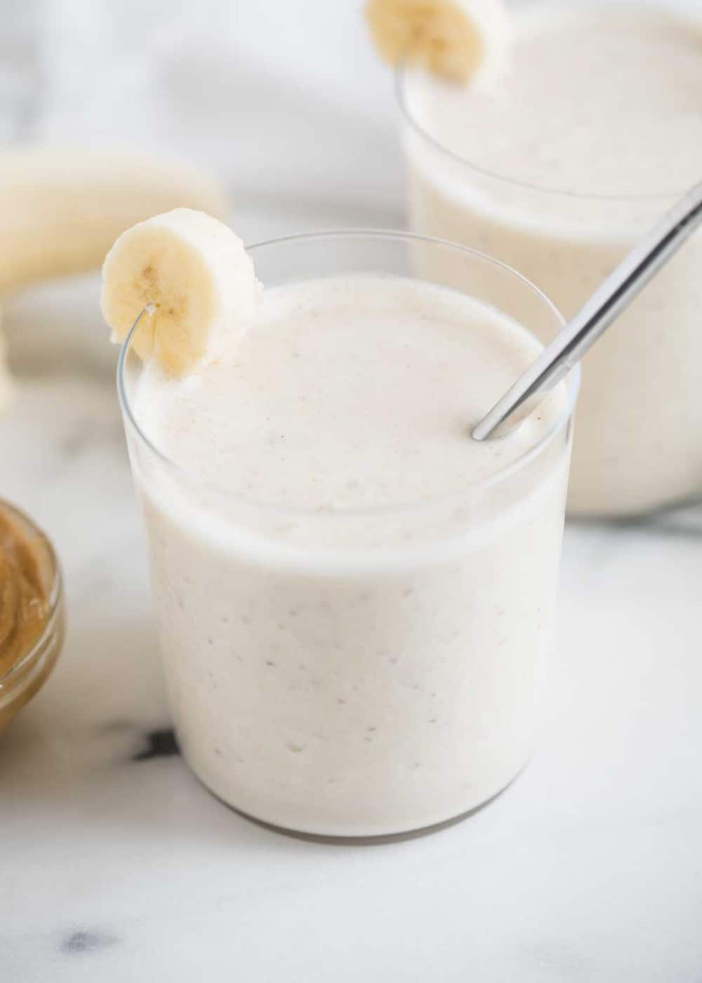 Peanut butter smoothie in a glass with a silver straw.