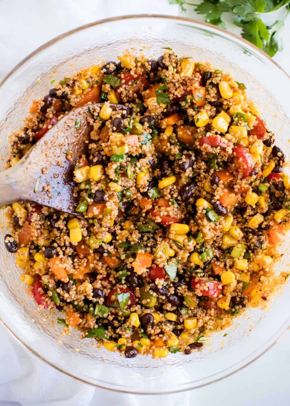 Southwest quinoa salad in bowl with wooden spoon.