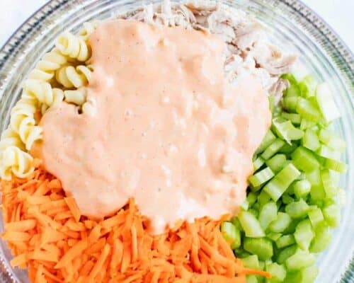 buffalo chicken pasta salad ingredients in a clear bowl