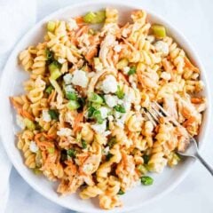 Buffalo chicken pasta salad in a white bowl with rotini, shredded chicken, carrots, celery, and creamy buffalo ranch dressing.