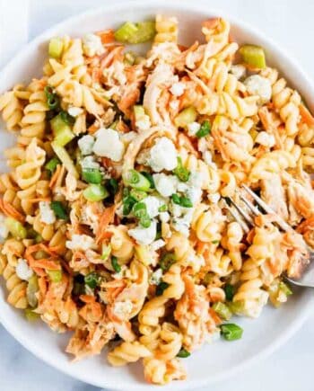 Buffalo chicken pasta salad in a white bowl with rotini, shredded chicken, carrots, celery, and creamy buffalo ranch dressing.
