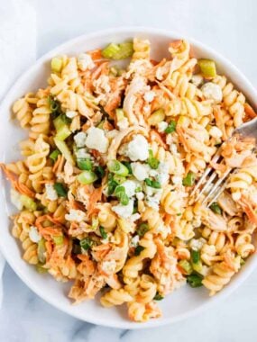 Buffalo chicken pasta salad served in a white bowl with rotini pasta, shredded chicken, carrots, celery, and a creamy buffalo ranch dressing.