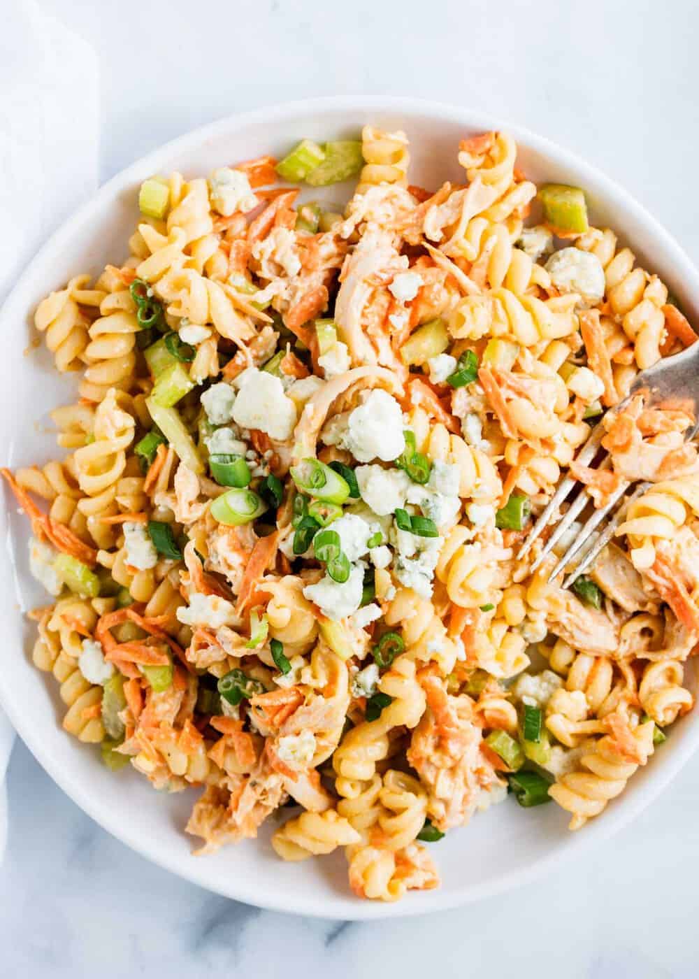 Buffalo chicken pasta salad on a white plate with fork.