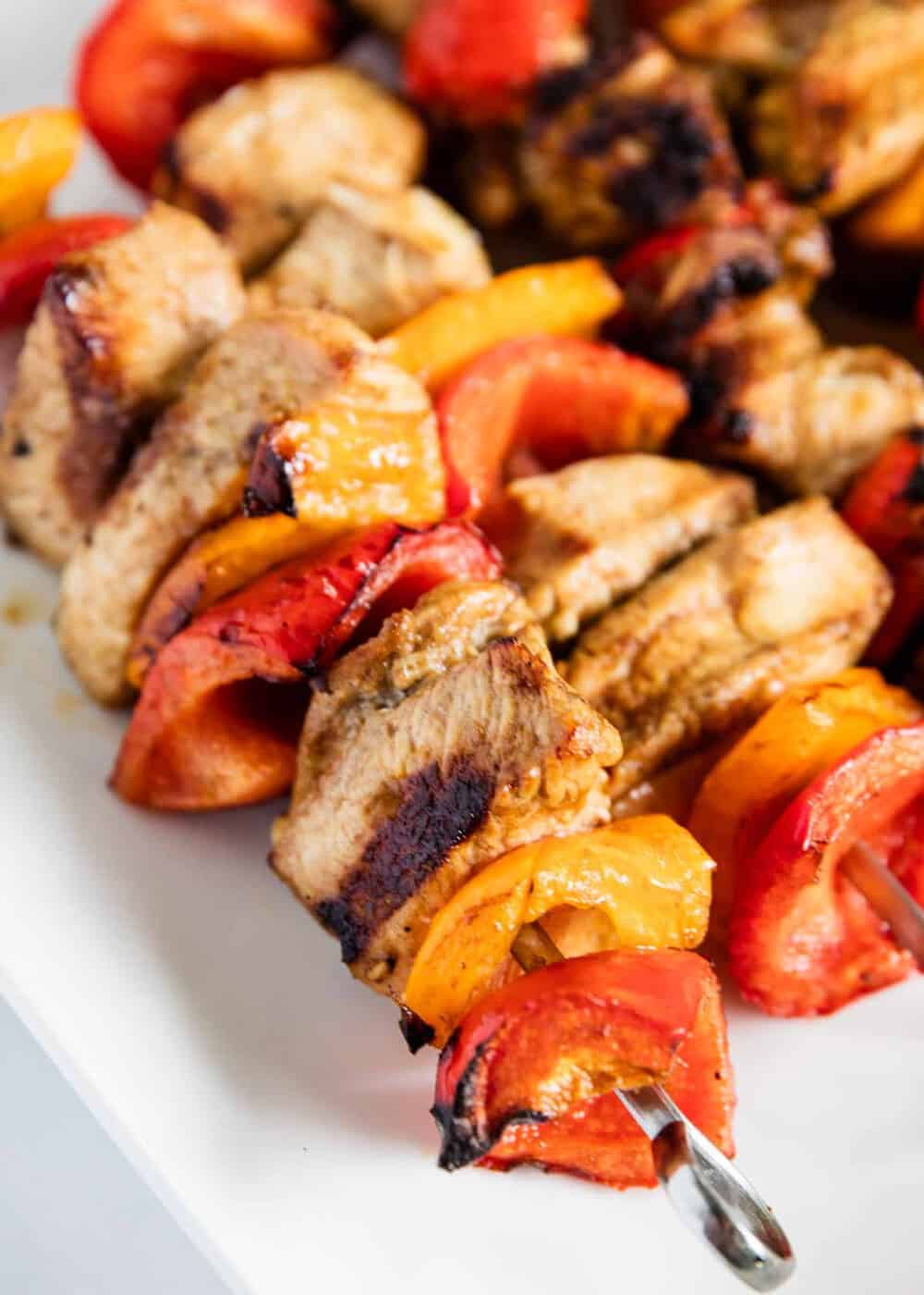 Cooked chicken kabobs on white plate.