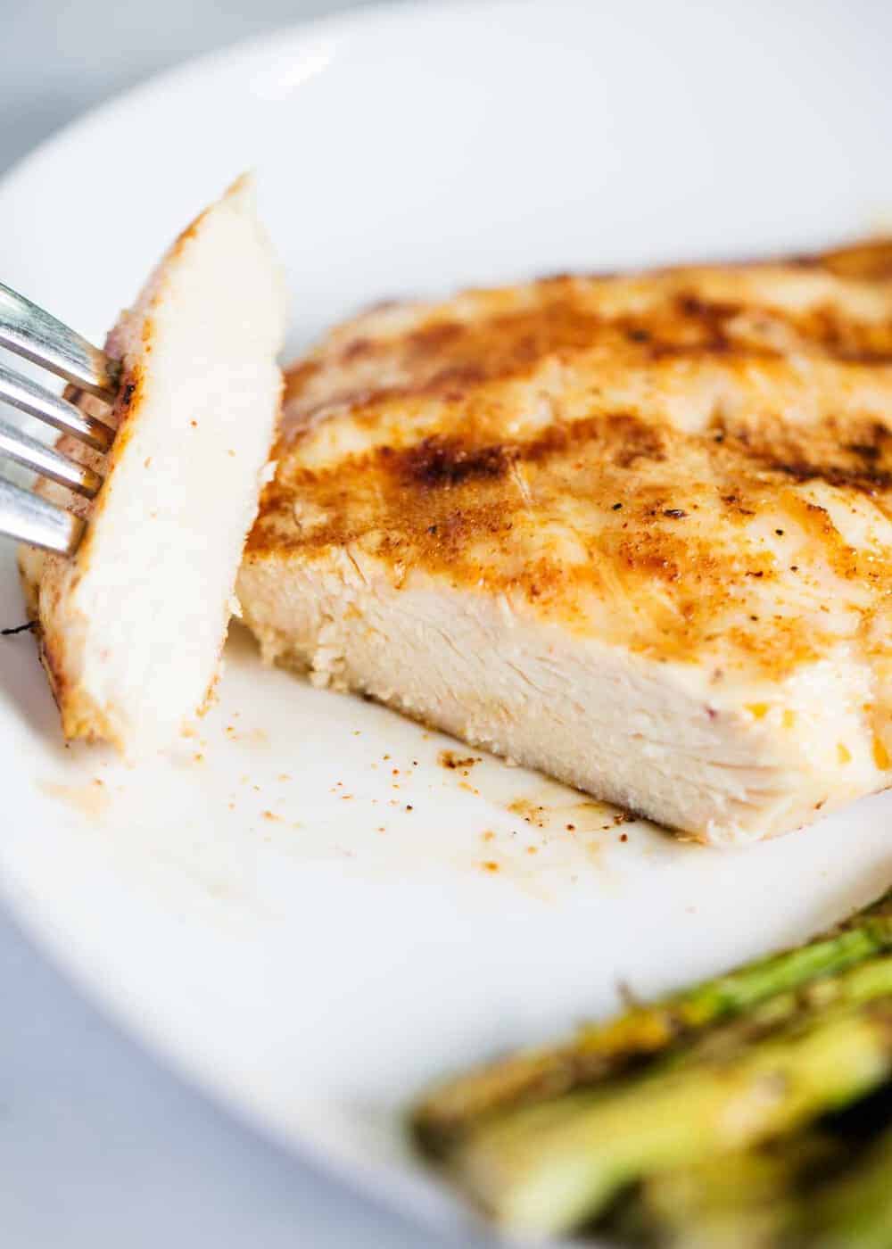 Sliced grilled chicken breast on white plate.
