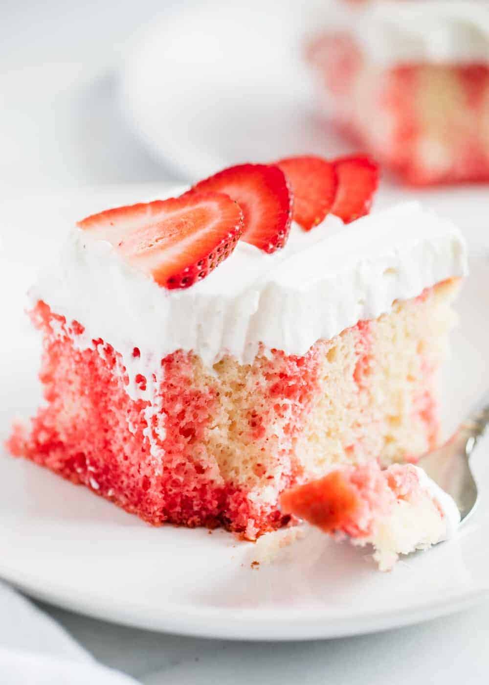 Jello poke cake with whipped cream and strawberries.