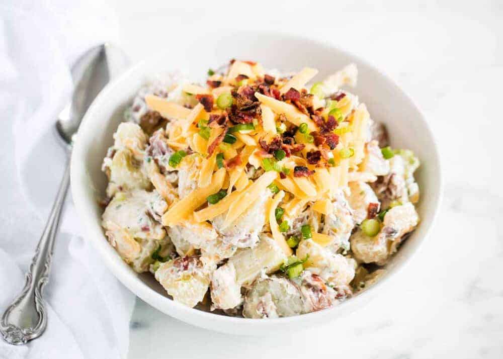 Loaded potato salad in white bowl.