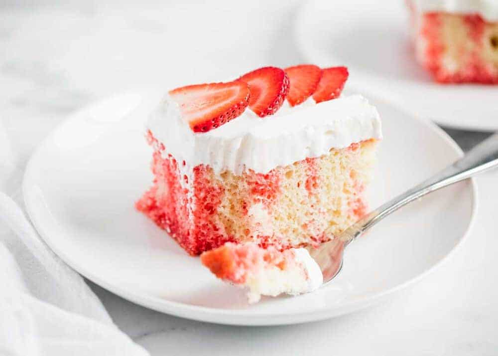 Strawberry poke cake on a white plate.