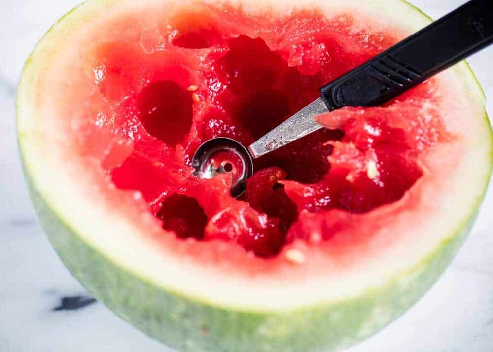 Watermelon being scooped out with melon baller.