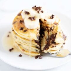 Stack of buttermilk chocolate chip pancakes on white plate.