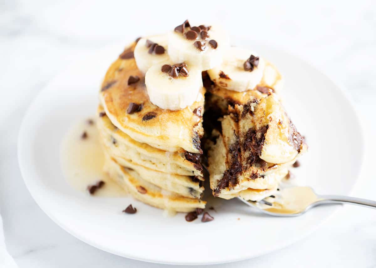 Stack of chocolate chip pancakes on white plate.