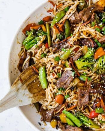 beef ramen in a pan with a wooden spoon