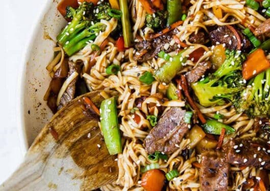 beef ramen in a pan with a wooden spoon