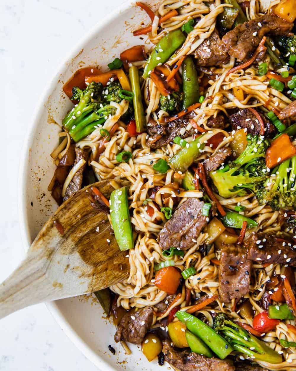 Beef ramen noodles in pan with wooden spoon.