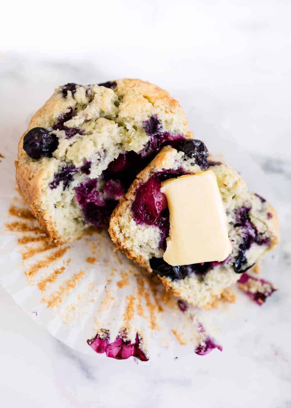 Blueberry muffin sliced in half with butter on top.