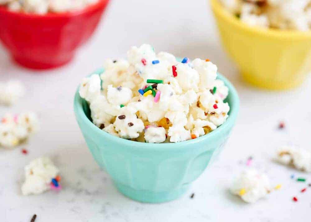 Blue bowl of cake batter popcorn with sprinkles.