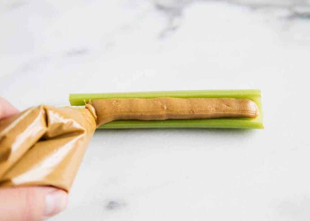 piping peanut butter into a celery stick