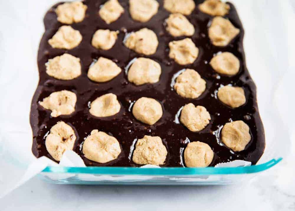 Drops of peanut butter filling on top of brownie mixture in pan.