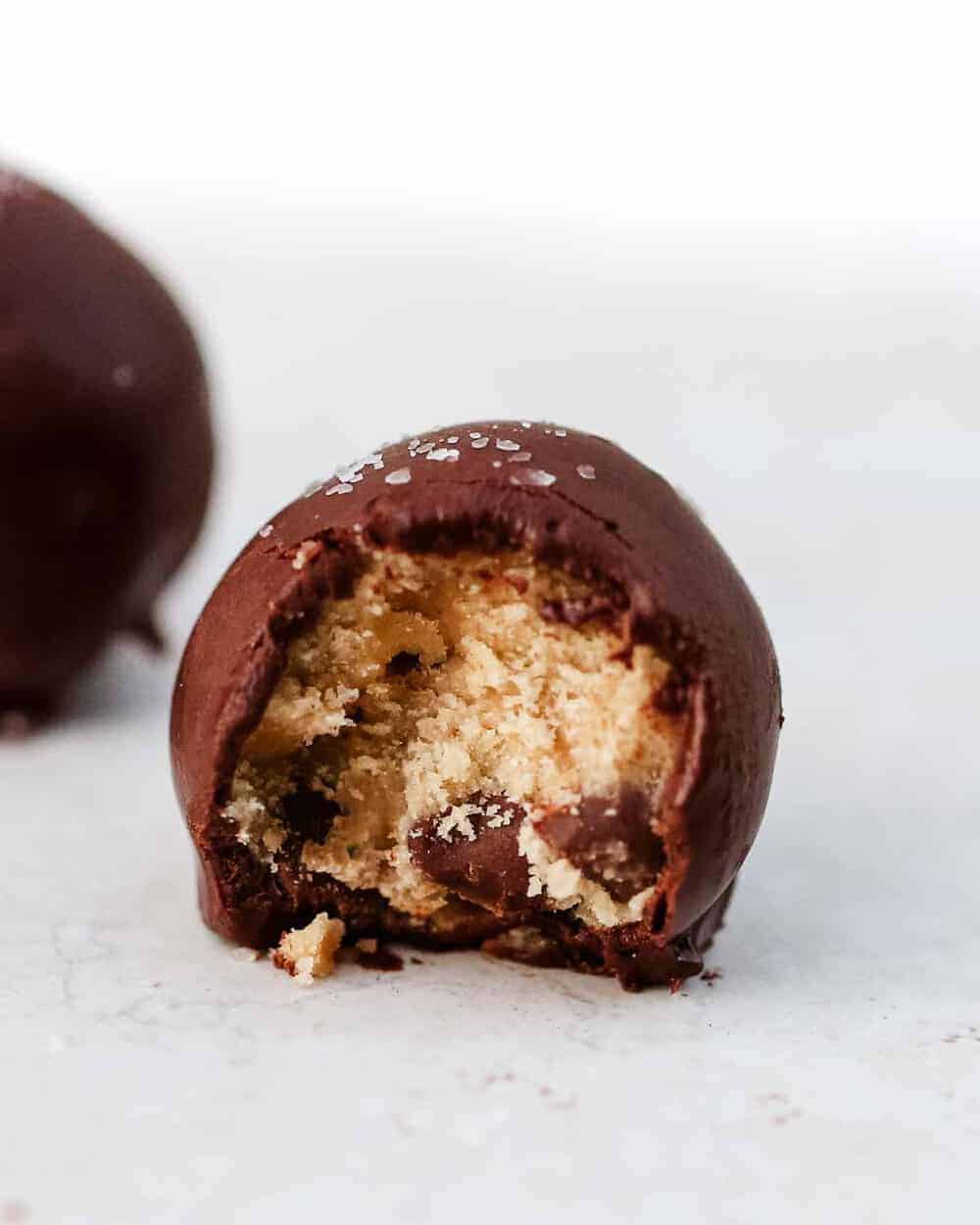 Cookie dough truffle with a bite taken out.