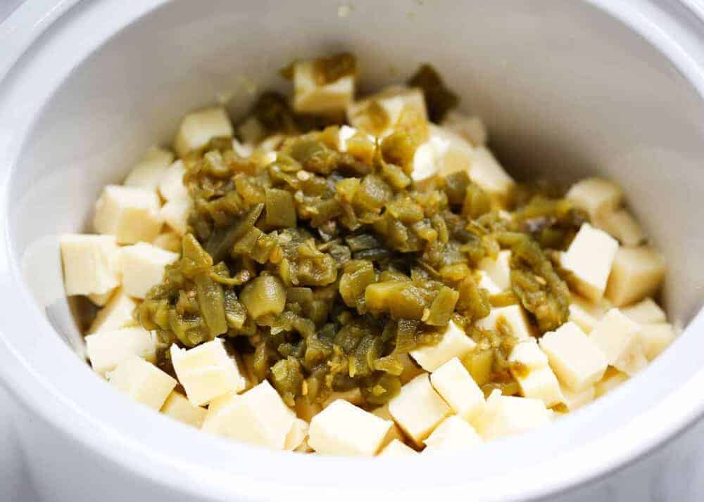 White cheese cubes and green chiles in crockpot.