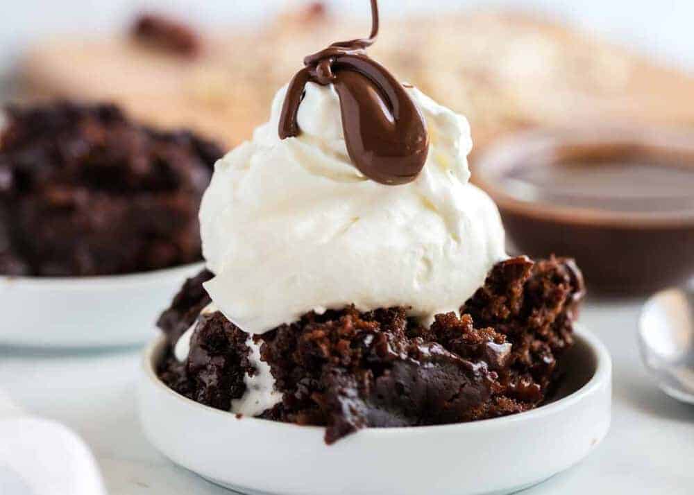 Bowl of crockpot chocolate cake topped with ice cream and hot fudge.