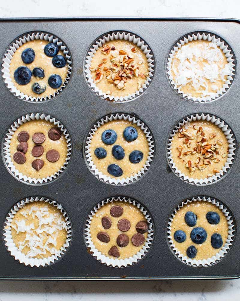 oatmeal muffin batter in muffin tin with different toppings sprinkled on 