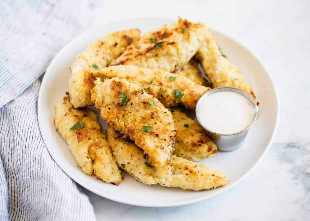 Homemade chicken tenders on white plate with ranch.