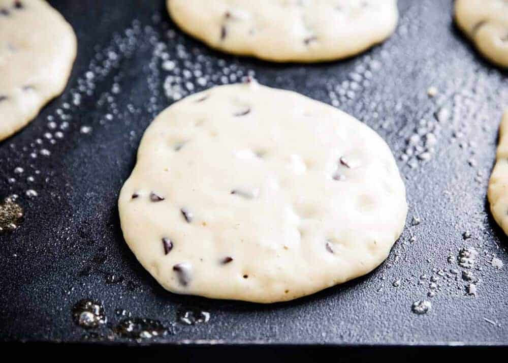 Cooking homemade chocolate chip pancakes on a griddle.