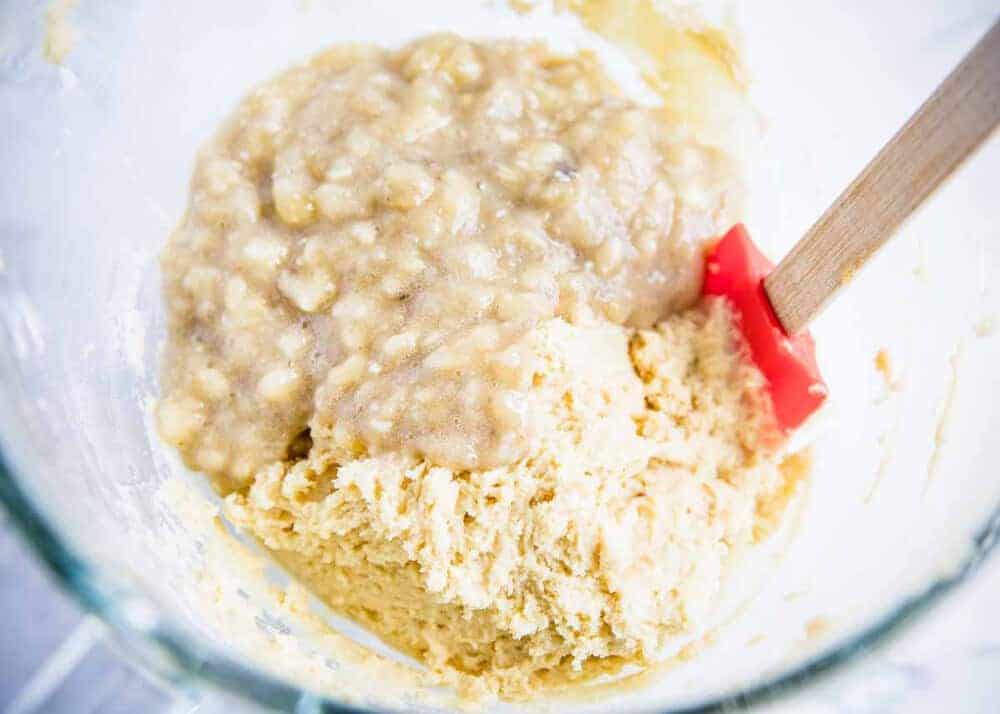 Folding in mashed bananas to banana bar batter with a spatula.