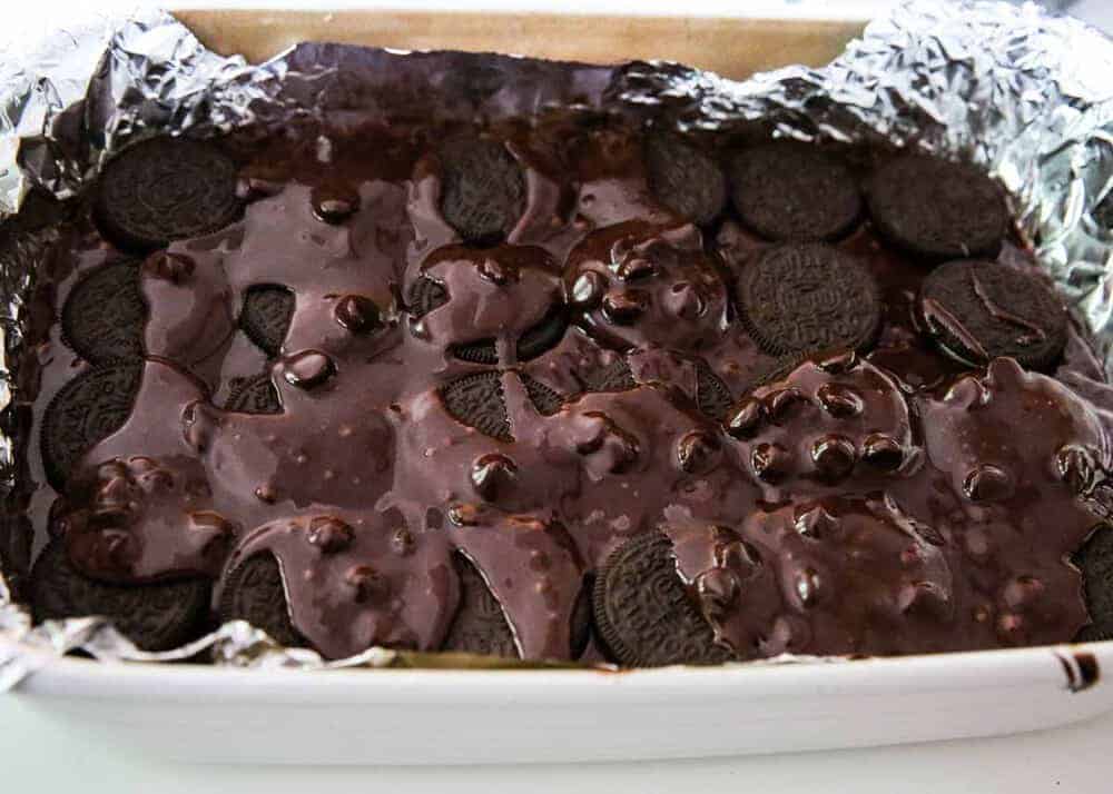 pouring remaining brownie batter over oreo layer in baking dish