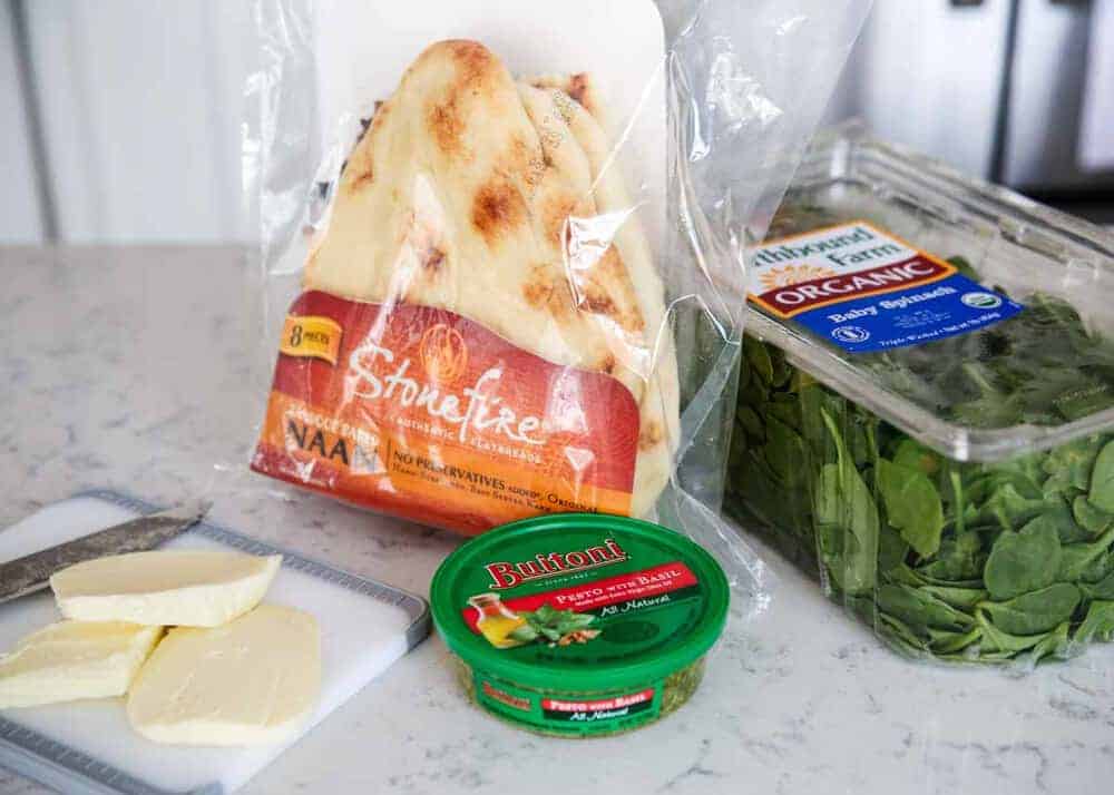 Pesto pizza ingredients on counter top.